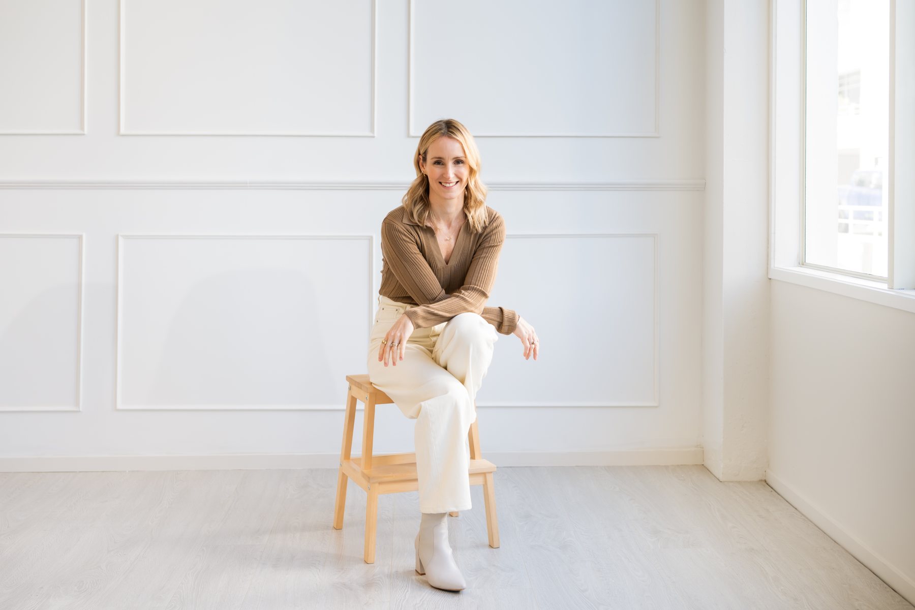 Natalie sitting on a wooden stool, smiling